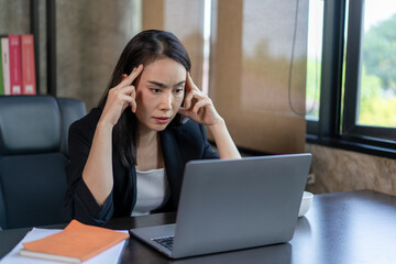 A woman is sitting at a desk with a laptop and a stack of books