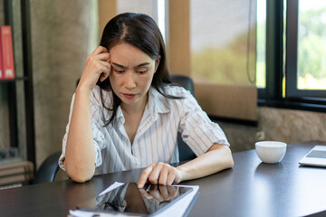 A woman is sitting at a desk with a tablet in front of her