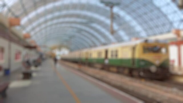 Bokeh view of suburban train arriving at local railway station in Chennai, India. Blurred background footage.