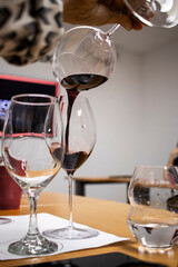 Sommelier pouring red wine between two glasses during wine tasting