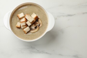 Delicious mushroom cream soup with croutons on white marble table, top view. Space for text