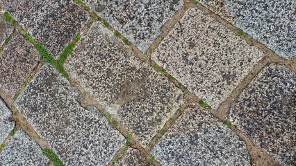 Cobblestone Pavement Close-Up with Grass Growing Between Stones