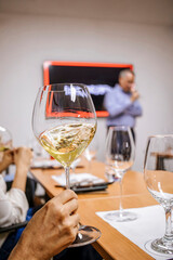Hand holding a glass of swirling white wine during an engaging wine tasting session