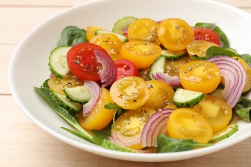 Fresh salad with yellow tomatoes on wooden table, closeup