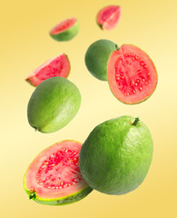 Fresh guava fruits falling on pale orange background