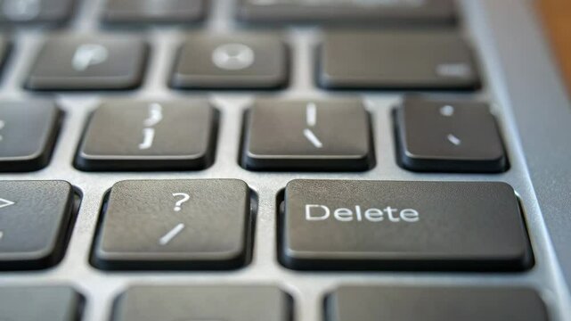 Close up of finger pressing delete key on keyboard for computer input technology symbolizing termination of digital content and control