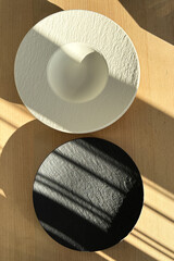 White and black plates on the wooden table.
