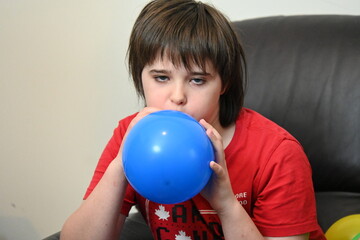child blowing up balloons for birthday