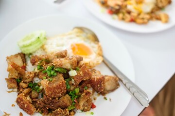 A plate of crispy pork belly stir fry with holy basil (kra pao moo grob), white rice and a fried egg at a street food stall at Soi 20 - Silom, Bangkok, Thailand
