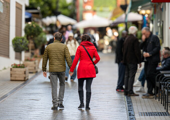 tourist couple holding hands and walking on stone street 