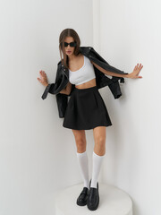 Fashion model showcases edgy style in sleek studio setting with playful poses