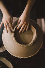 Hands skillfully shape a clay pot in a pottery studio. The workshop encourages creativity and focuses on teaching pottery techniques to beginners in a relaxed atmosphere.