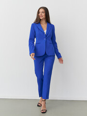Stunning female model showcases vibrant blue suit in modern fashion studio setting
