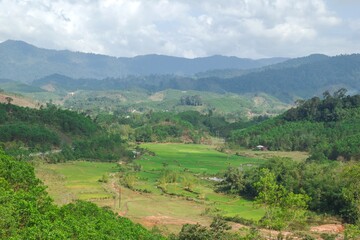Naklejka premium Lush Green Valley Surrounded by Majestic Mountains and Tranquil River in Prao, Vietnam.