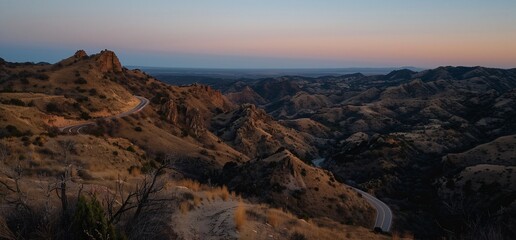 Obraz premium High desert landscape at sunset. Rolling hills, winding road, and distant valley