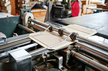 Efficient machine folding cardboard flaps in a bustling packaging facility during a productive daytime operation
