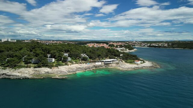 Aerial view of seafront buildings merged with dense green vegetation on the shore of Pula, Croatia