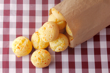homemade cheese bread, traditional Brazilian snack, in a rustic paper bag on a kitchen table