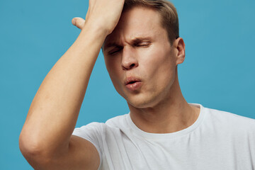 frustrated young caucasian man wear white t-shirt touch forehead with closed eyes isolated on grey...
