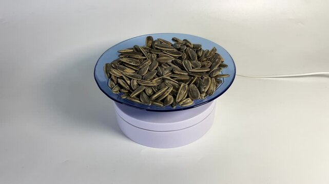 a plate of sunflower seeds rotating on a white background