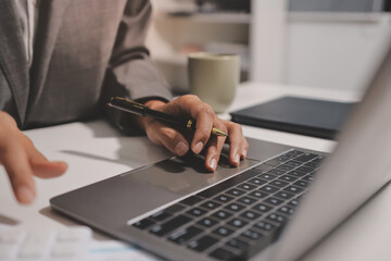 Working from home, Closeup business woman using laptop computer and analyzing financial report.