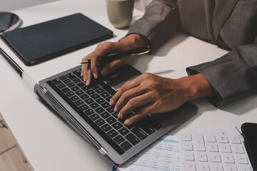 Working from home, Closeup business woman using laptop computer and analyzing financial report.