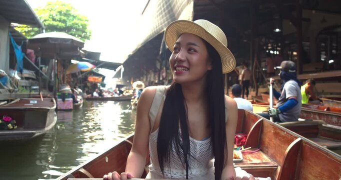 Young Asian tourist woman cheerful and happy to eat street food and sight seeing travel by boat along the canel at Damnoen Saduak Floating Market Thailand