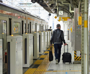 名古屋駅のホームでスーツケースを持って乗車するシニア男性の姿