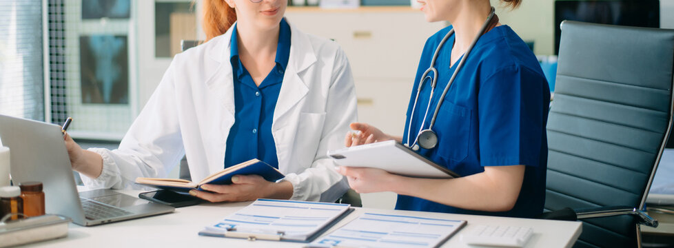 Doctor and nurse team using tablet to review medical results. Diverse healthcare professionals in modern hospital clinic