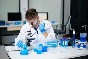 male scientist working with micro pipettes analyzing biochemical samples, advanced science chemical...