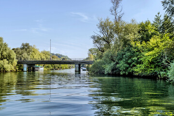 A peaceful river scene with a bridge and lush trees reflecting on the water.