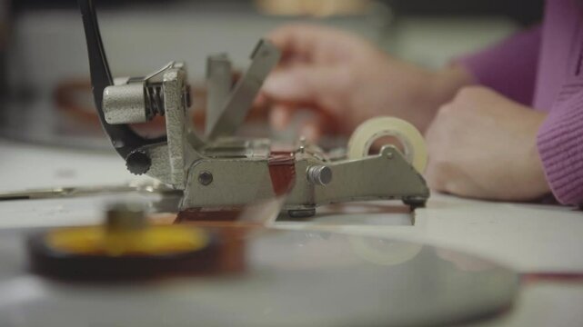 Persona manipulando pel&iacute;cula f&iacute;lmica de 16mm o 35mm en mesa de montaje f&iacute;sico. Montaje, Cine anal&oacute;gico, moviola, edici&oacute;n tradicional, cinematograf&iacute;a, historia del cine.