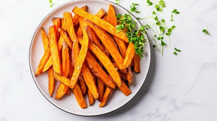 A plate of caramelized sweet potato fries with microgreens on the side, placed against a white marble background, shot from above in a close-up view to capture its vibrant orange color and crispy