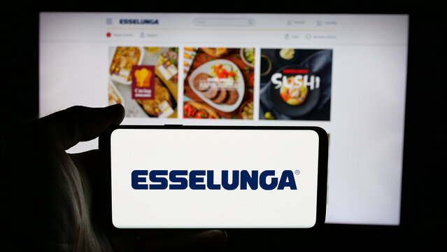 Stuttgart, Germany - 04-28-2025: Person holding cellphone with logo of Italian retail company Esselunga S.p.A. on screen in front of webpage. Focus on phone display.