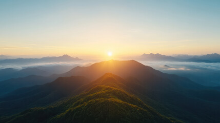 Golden sun rising over mountain peaks, illuminating landscape with warm light and serenity