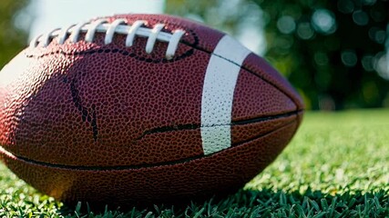 Close-up, low-angle shot of a football on grass, highlighting texture and detail, ideal for a sports video emphasizing game intensity.