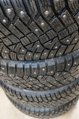 Close-up of studded winter tires with metal spikes stacked in storage. Premium winter automotive...