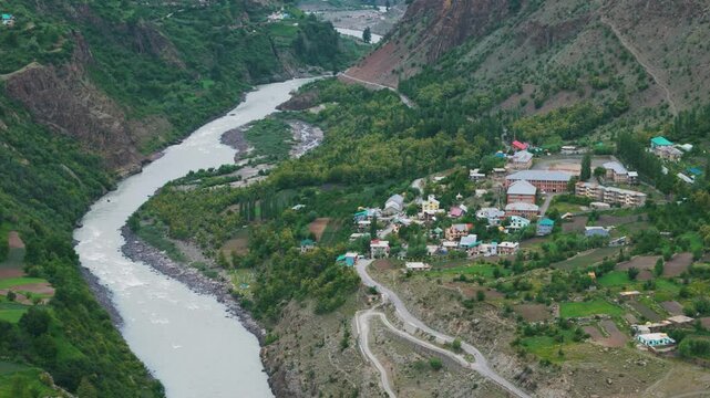 4K Aerial shot of beautiful small village near Chenab river flowing in Lahaul, Himachal Pradesh, India. River flowing in mountain valley. Summer in Himalayas.
