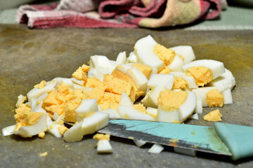 Finely chopped chicken eggs for making a salad lie on a cutting board on the table.