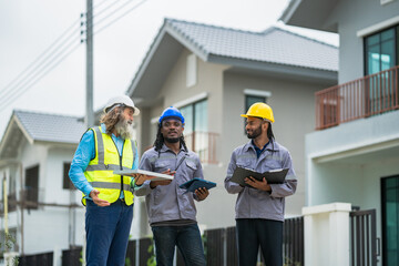 Three construction workers are standing outside a house, discussing plans for the project. Scene is professional and focused, as the workers are wearing safety gear and carrying blueprints