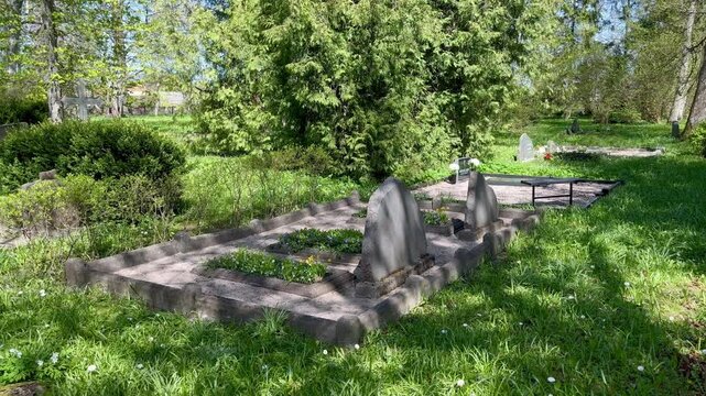 Old granite headstones among green spring grass at Doku Cemetery in quiet countryside