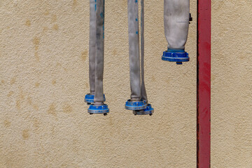 Fire hoses during drying – hung vertically against the background of a yellow plastered wall with a red structural element. Fire equipment during maintenance, close-up view