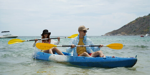 The young couple are happily navigating together in a light blue kayak with yellow paddles