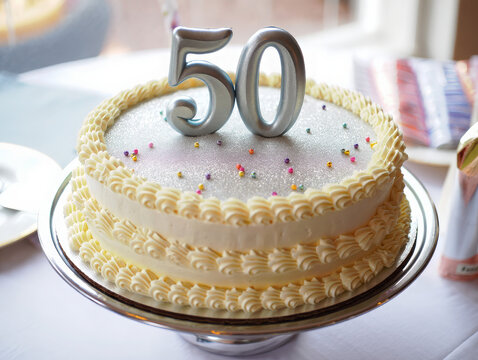 legant 50th birthday cake on a shiny silver cake stand, topped with a large number '50' in metallic silver