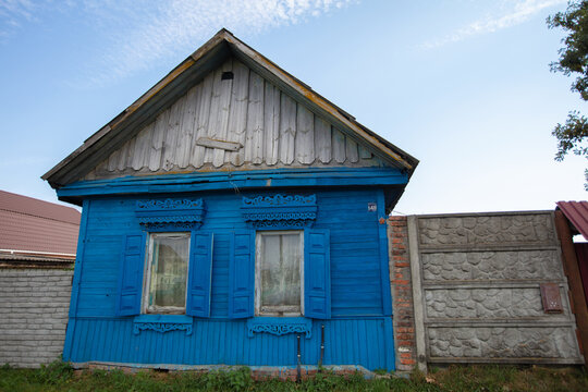 A blue rustic one-story wooden house with a gray roof and shutters on the windows.