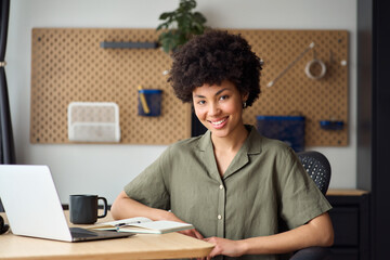 Young happy confident 20 years African American woman, pretty smiling girl student sitting at home desk with computer looking at camera, studying online, hybrid working. Portrait.