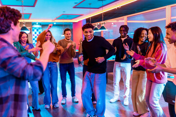 Multiethnic friends enjoying weekend dancing and games at bowling alley