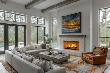 Modern farmhouse living room with large artwork above the fireplace, grey sofa, leather armchair, coffee table, and bright natural light