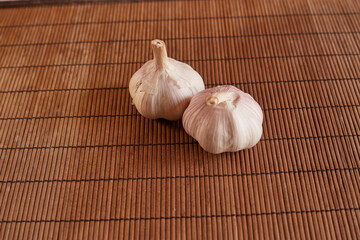 two whole garlic cloves on a wooden cutting board and,
