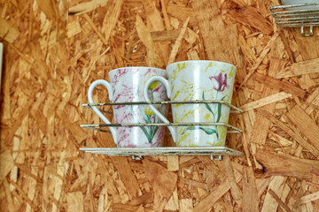 two cups on a shelf on the wall made of OSB . drying dishes.